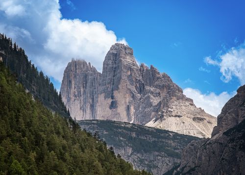 Free Stunning view of the Dolomites' rugged peaks, surrounded by lush forests under a vibrant blue sky. Stock Photo
