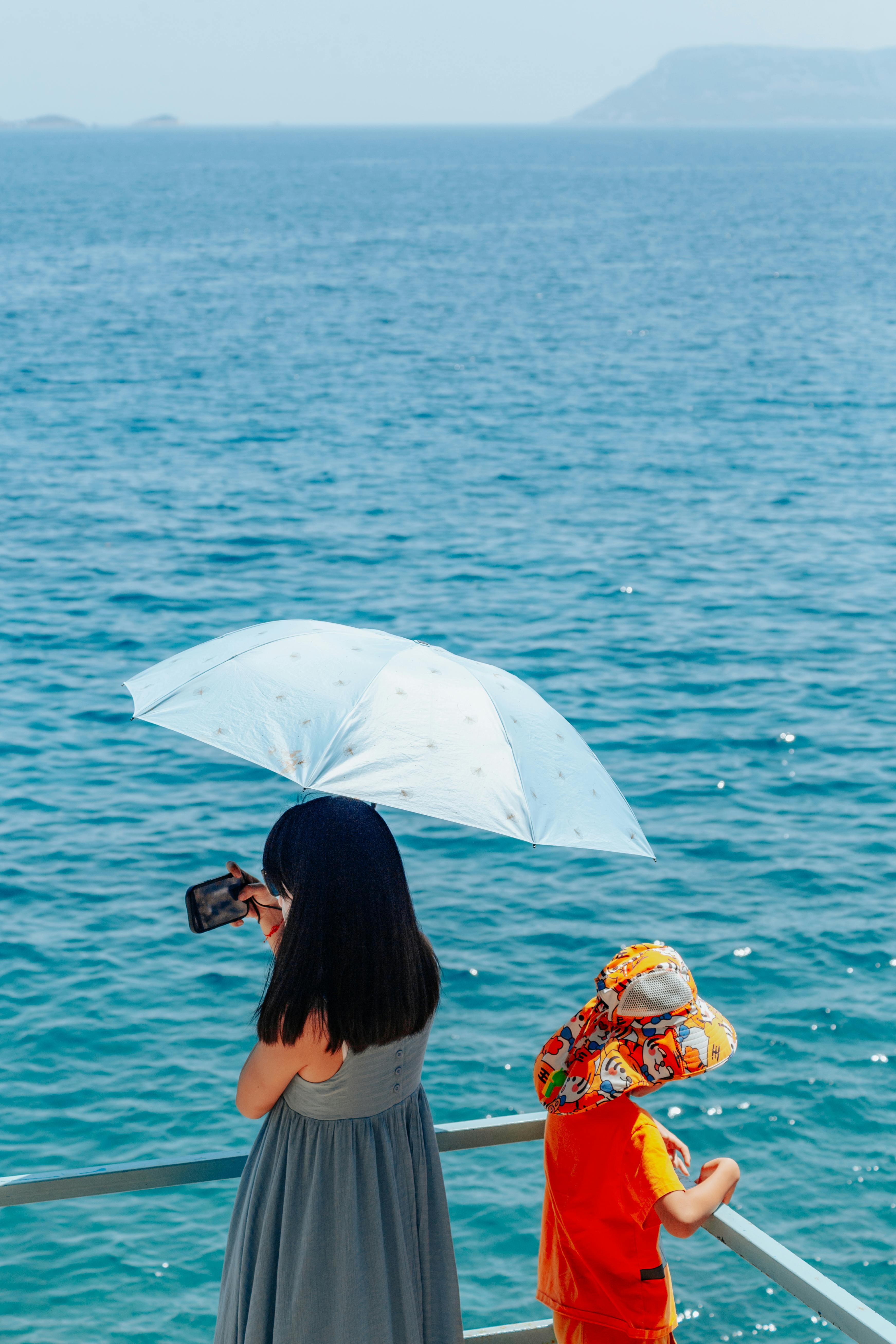 Woman and child capture summer memories by the sea in Kaş, Türkiye.