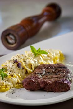 Juicy grilled steak served with creamy pasta and fresh herbs.