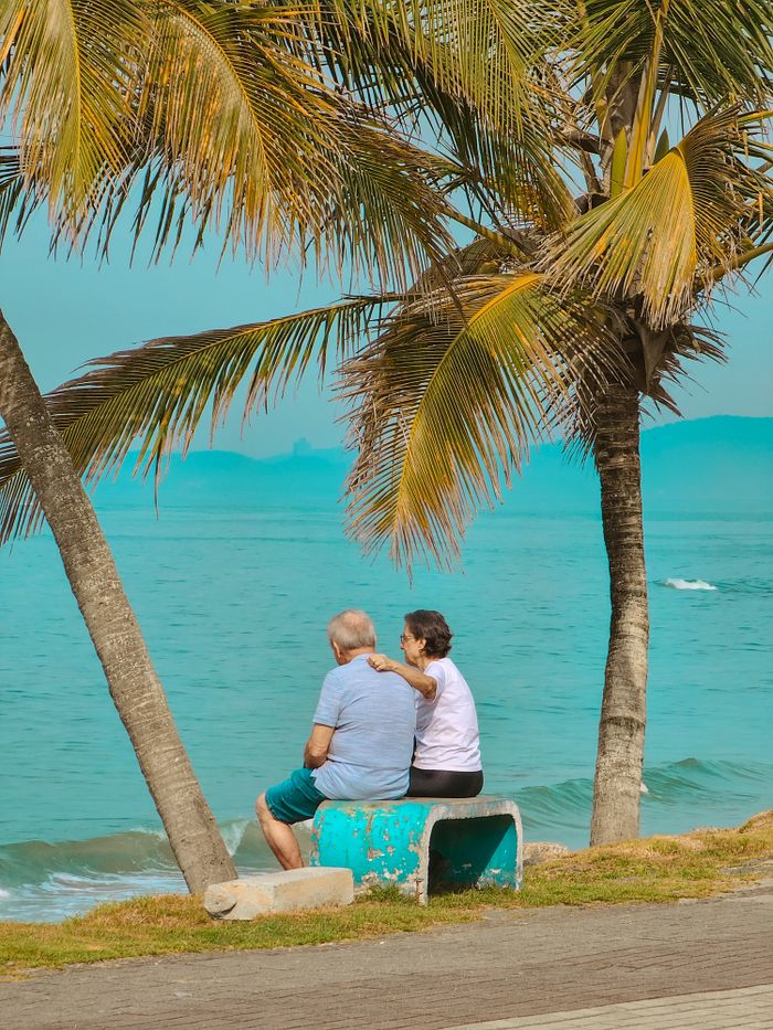 Couple assis sous les palmiers face à la mer
