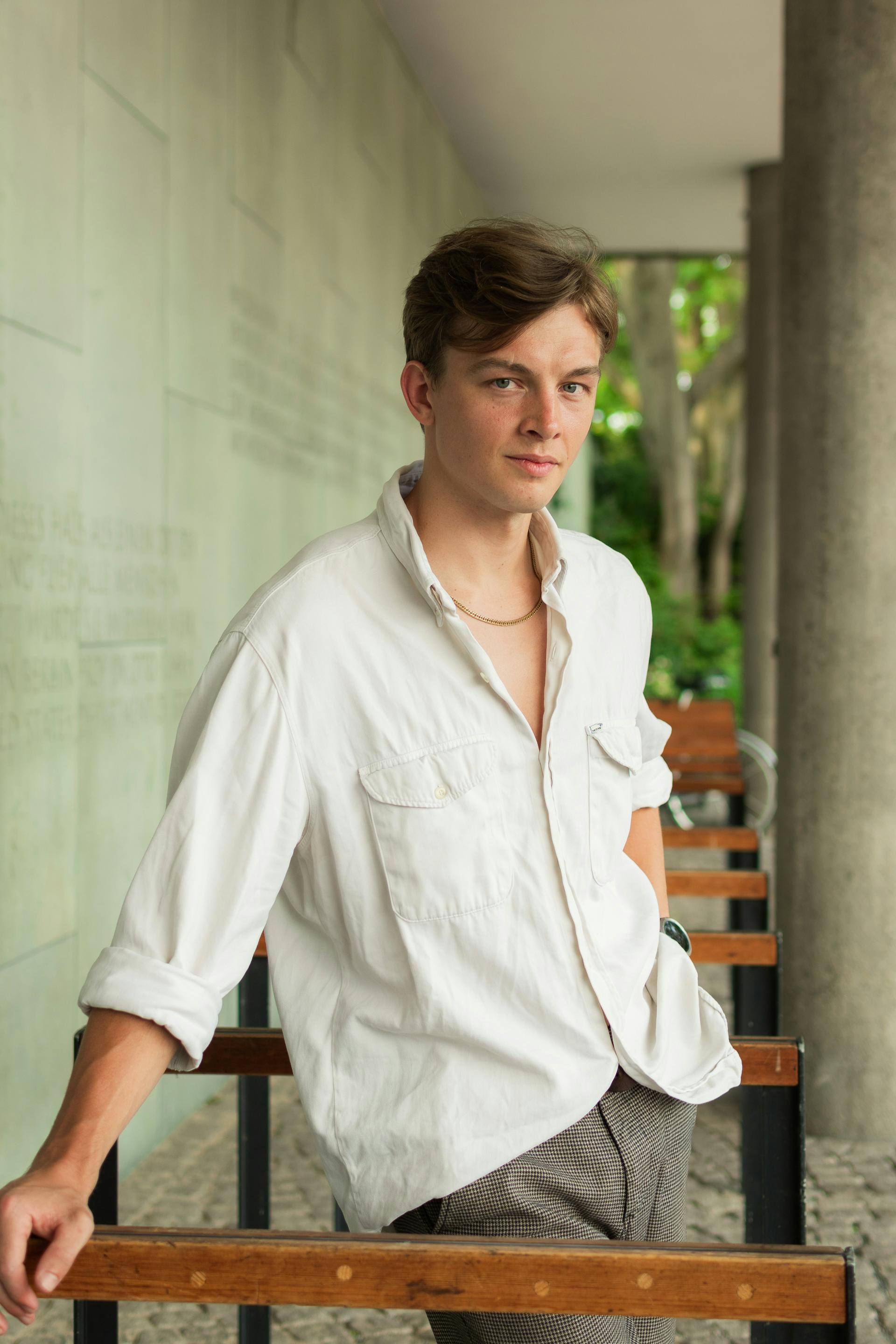 Young man in casual attire posing confidently in an urban setting, showcasing modern style.
