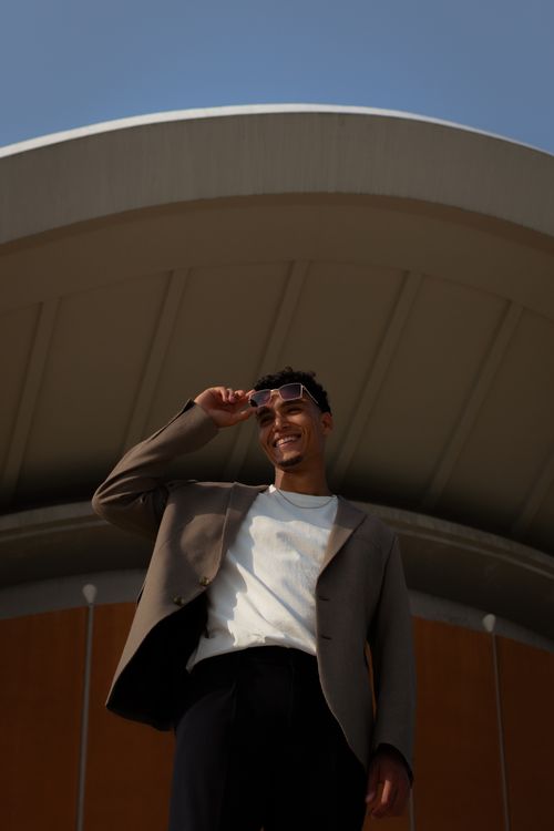Free A stylish man poses confidently in front of a modern architectural structure. Stock Photo