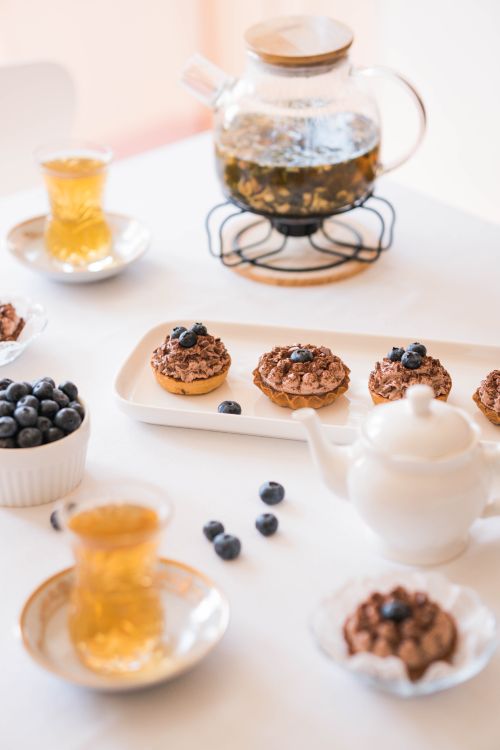 Free A beautifully arranged table featuring tea, blueberry desserts, and elegant dishware. Stock Photo