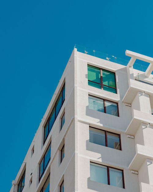 Free A modern white high-rise building against a clear blue sky, architectural design with large windows. Stock Photo