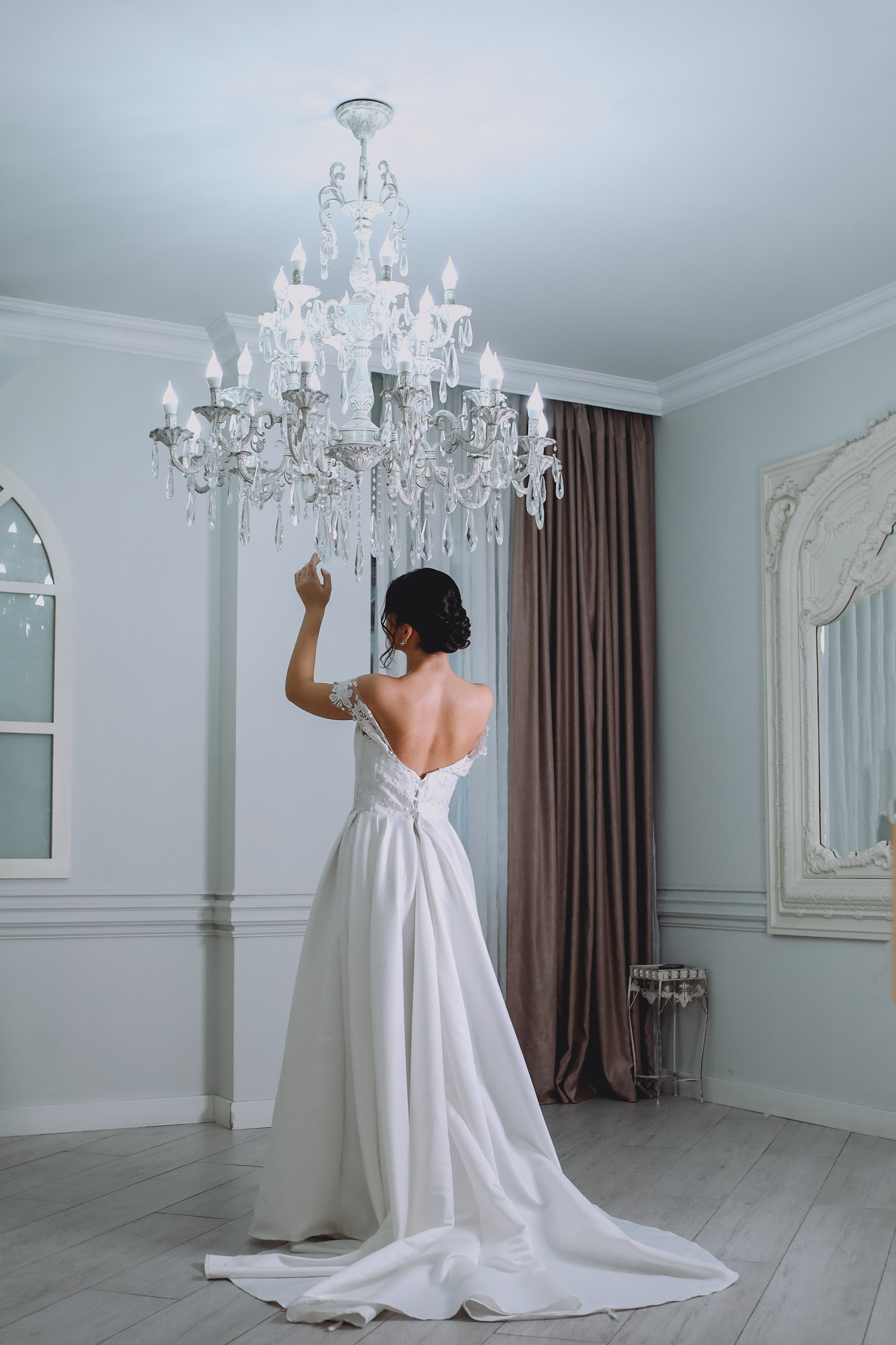 A woman in a wedding dress is standing in front of a chandelier · Free ...
