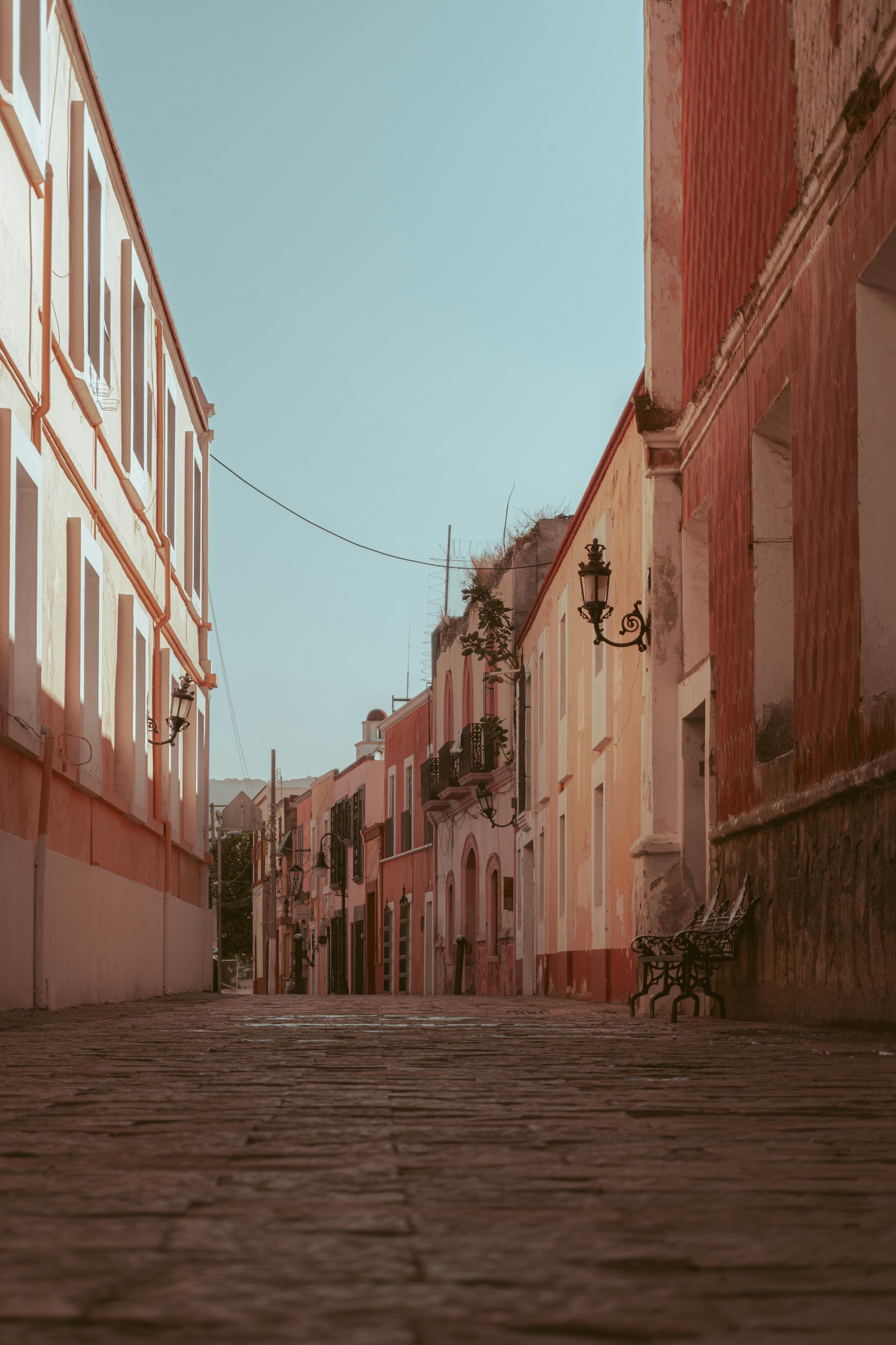 Explore the beauty of a narrow Atlixco street lined with vibrant rustic buildings under a clear sky.
