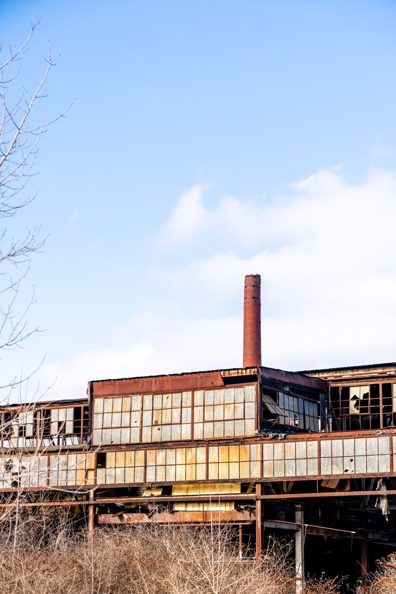 Old brick factory with a tall chimney under blue sky