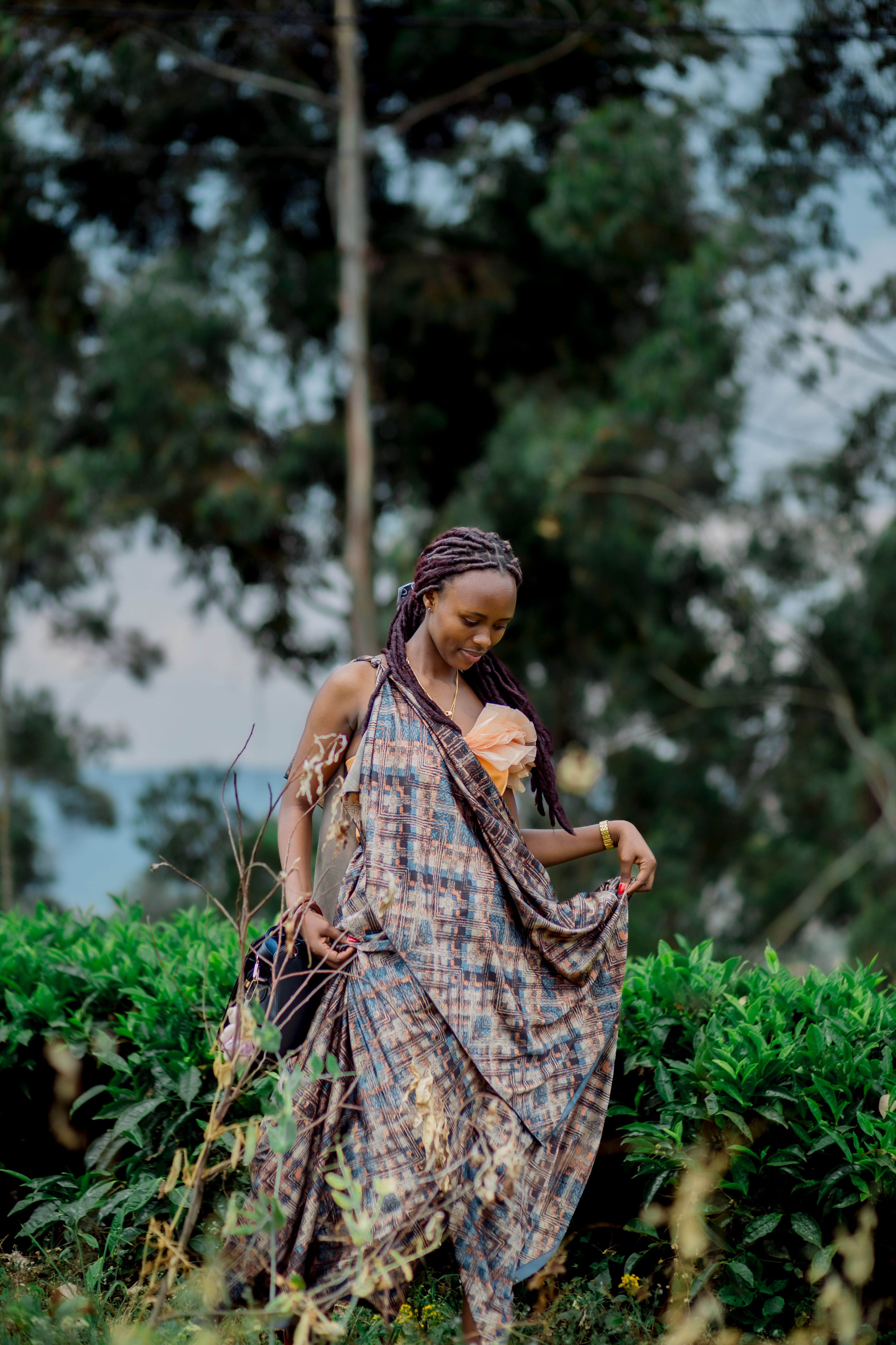 A woman peacefully enjoys nature, surrounded by greenery in a flowing dress.