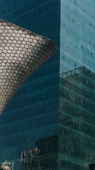 Reflective glass skyscraper beside modern hexagonal facade in Ciudad de México.
