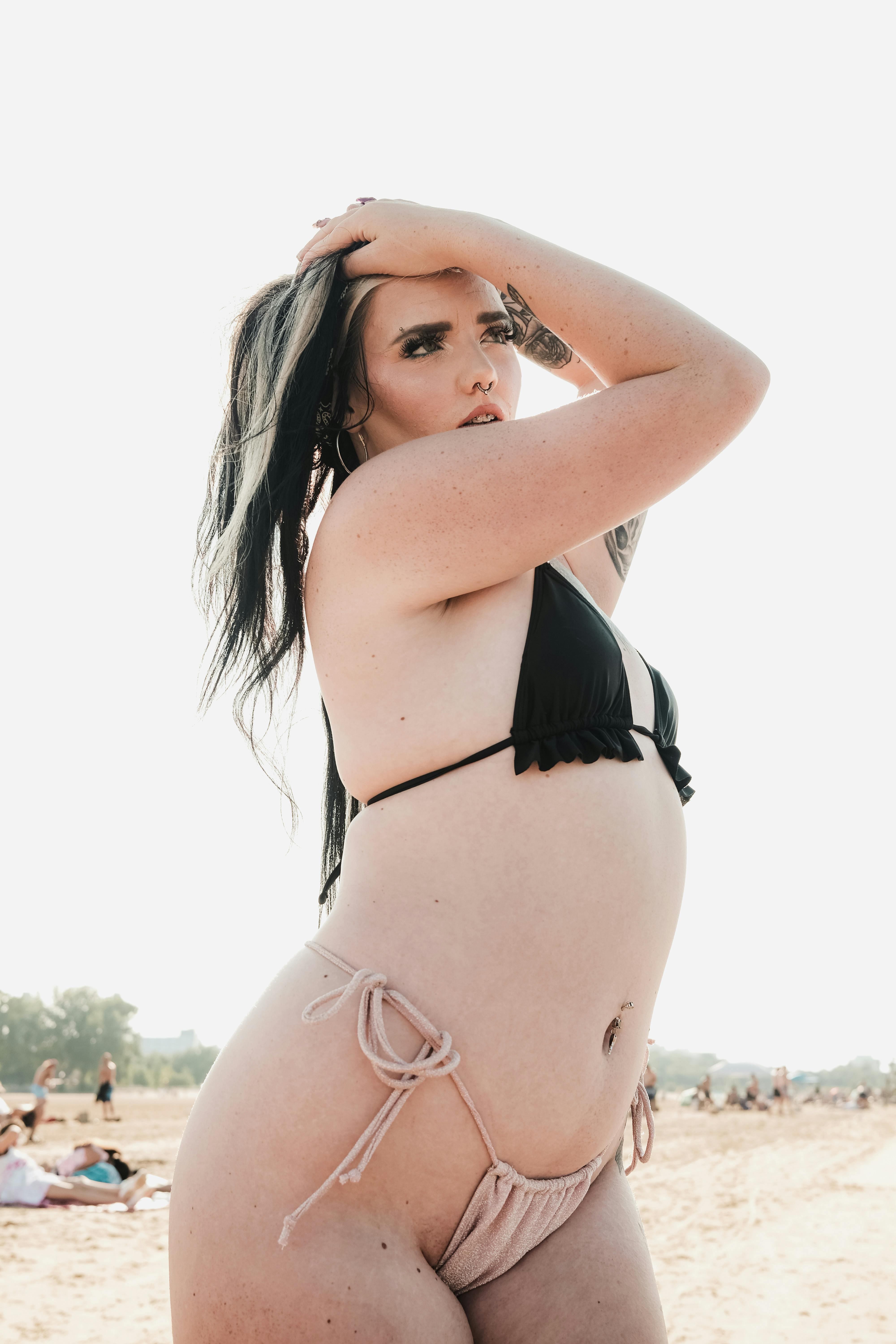 Confident woman posing in a bikini on a sunny beach, enjoying summer vacation.