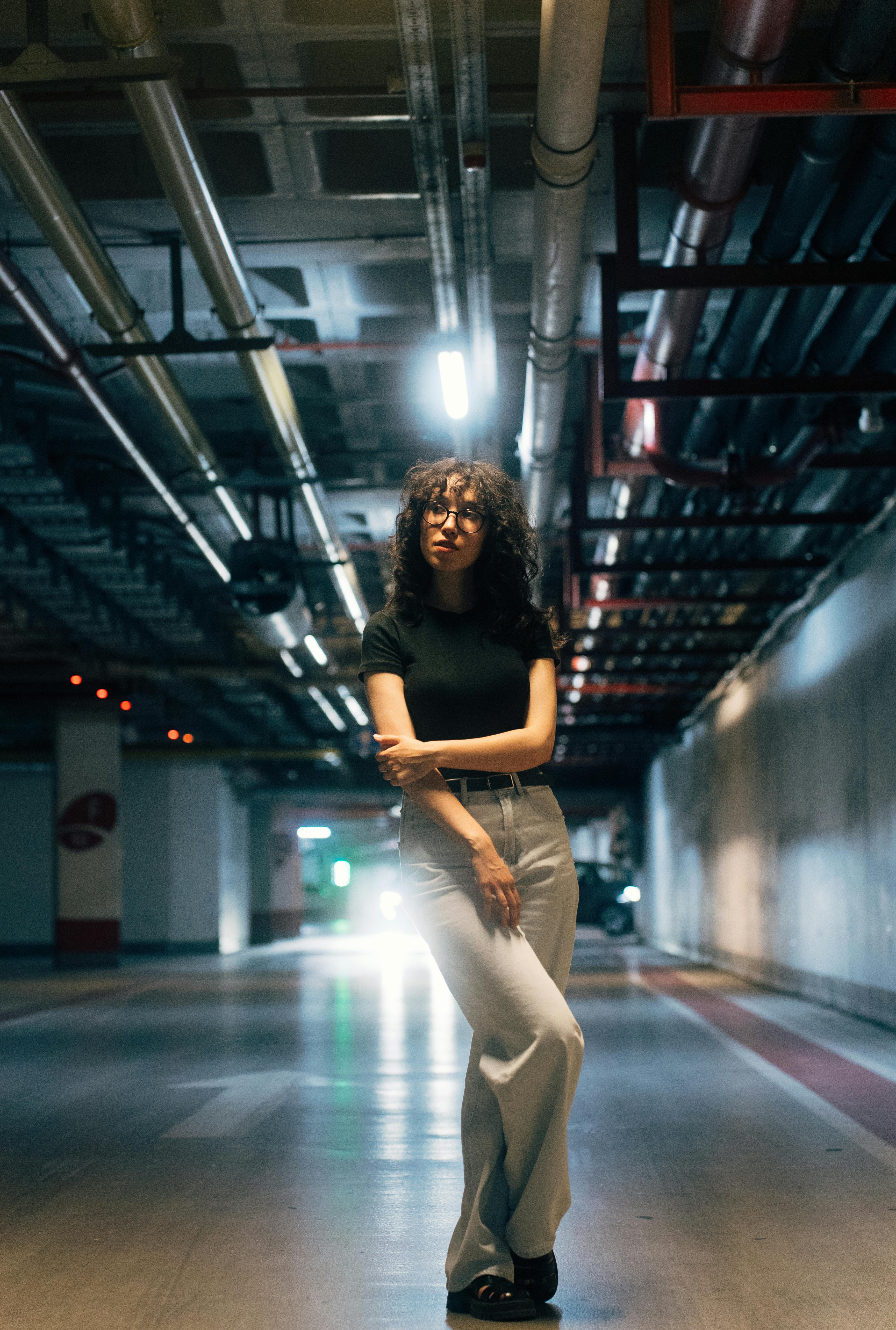 a woman standing in an empty parking garage