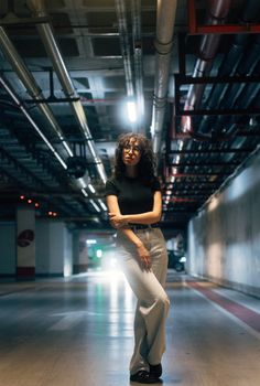 A fashionable woman stands confidently in a modern underground parking area.