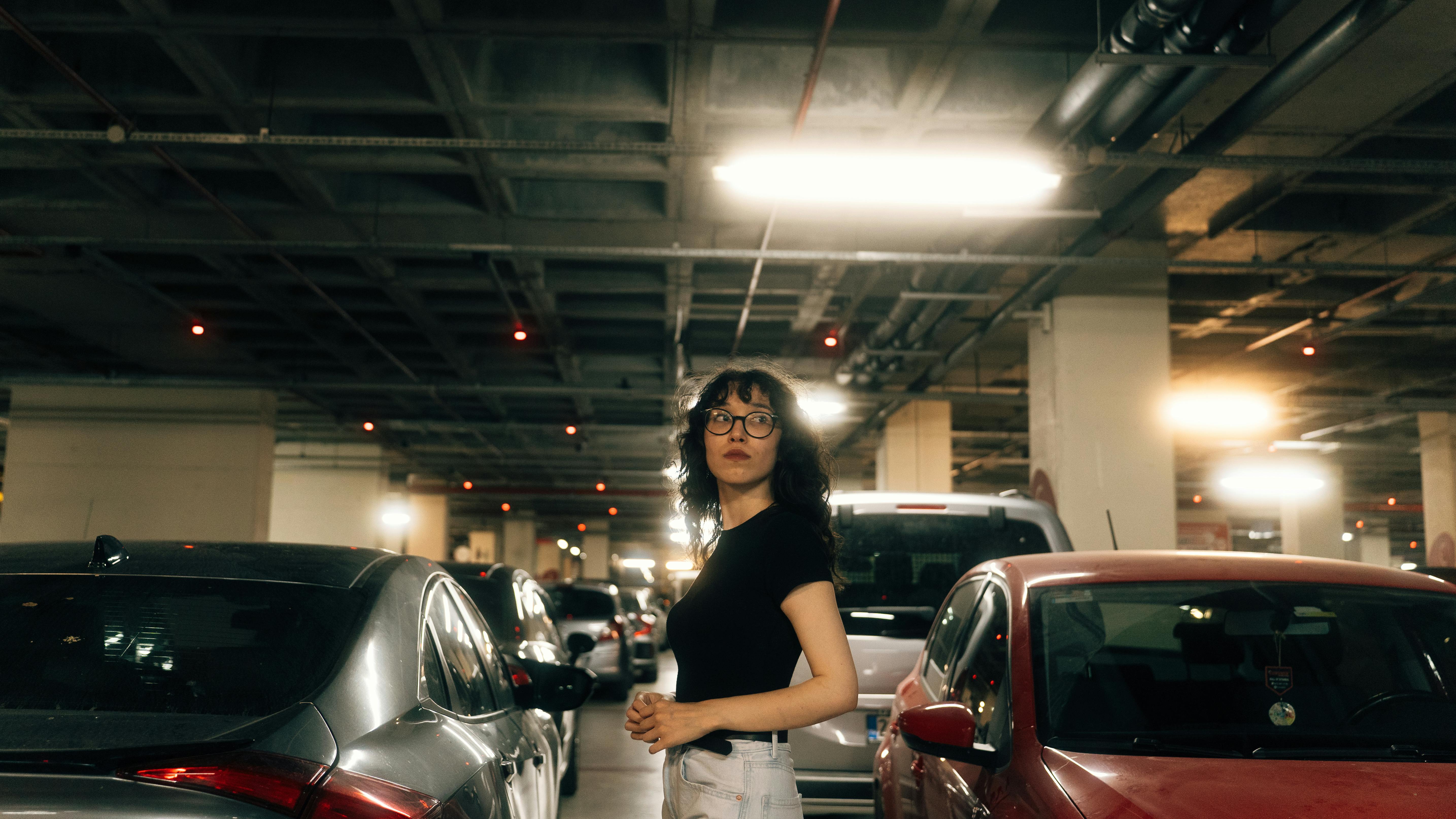 a woman standing in a parking garage with cars