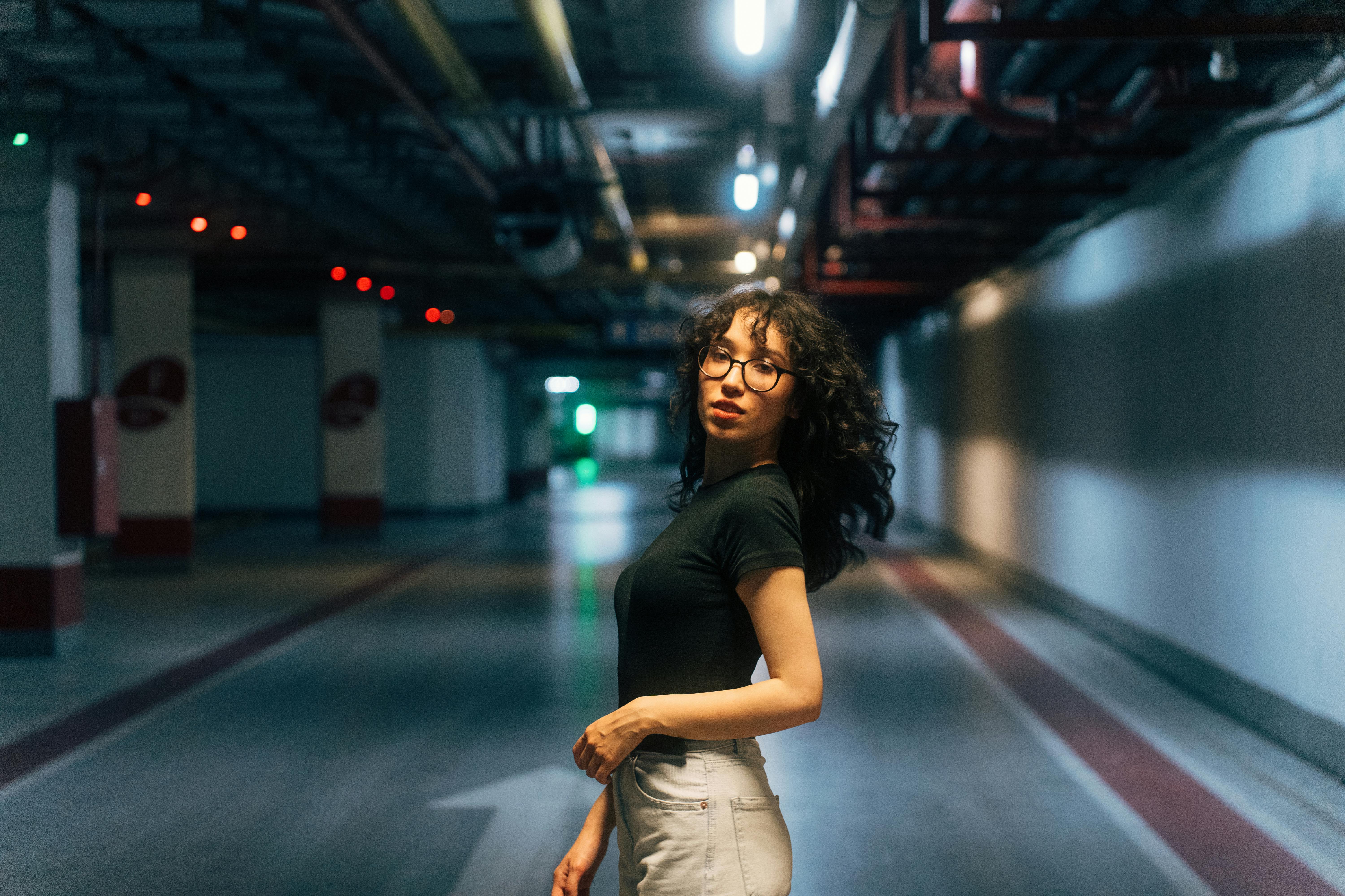 a woman standing in an empty parking garage