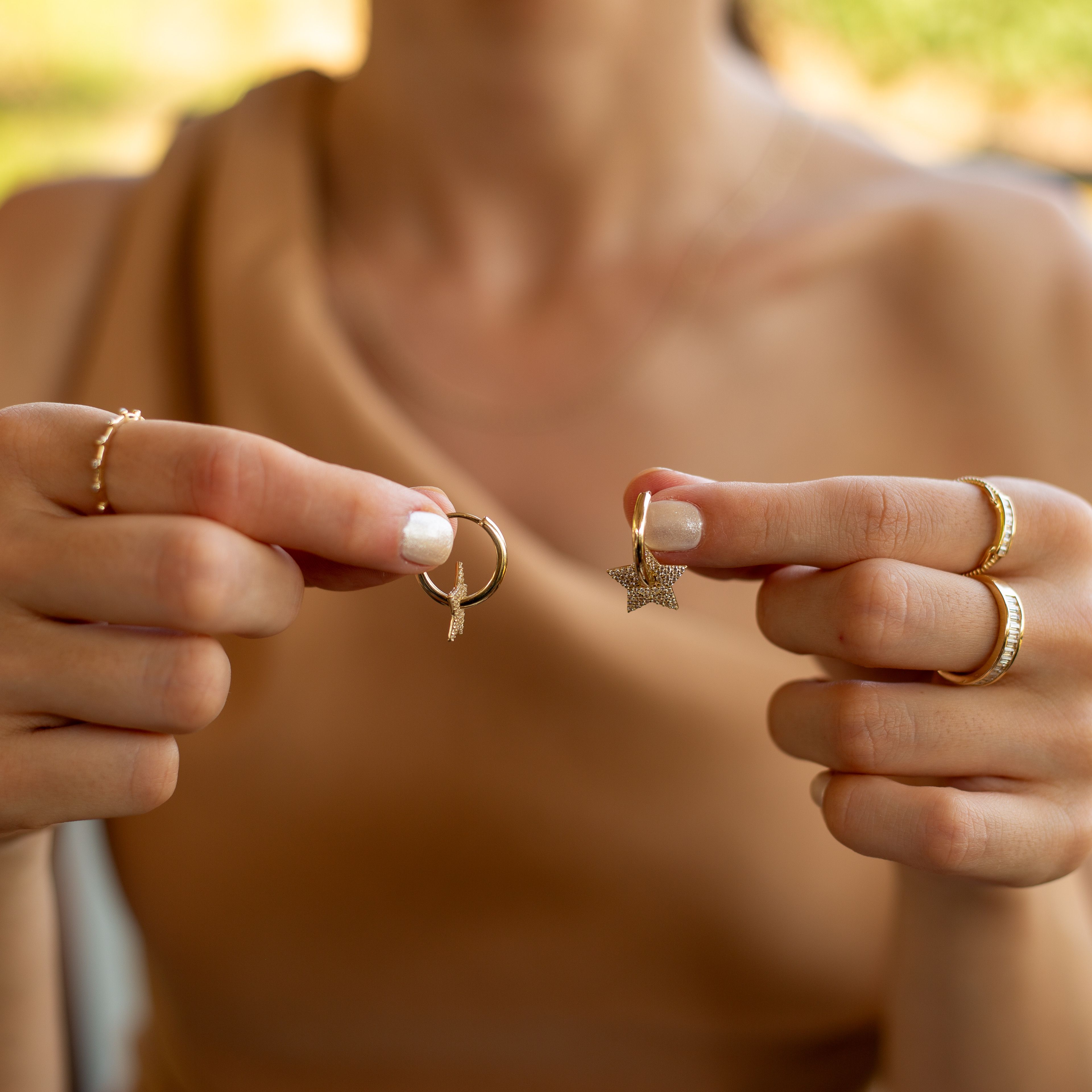 Close-up of a woman's hands holding gold star and moon earrings, showcasing elegant jewelry.
