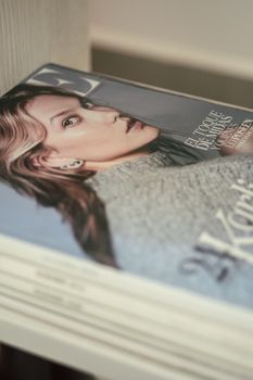 Stylish stack of Vogue magazines on a shelf with selective focus.