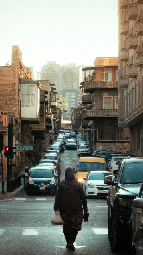 Free A bustling street scene featuring vehicles and pedestrian in an old city setting during the day. Stock Photo