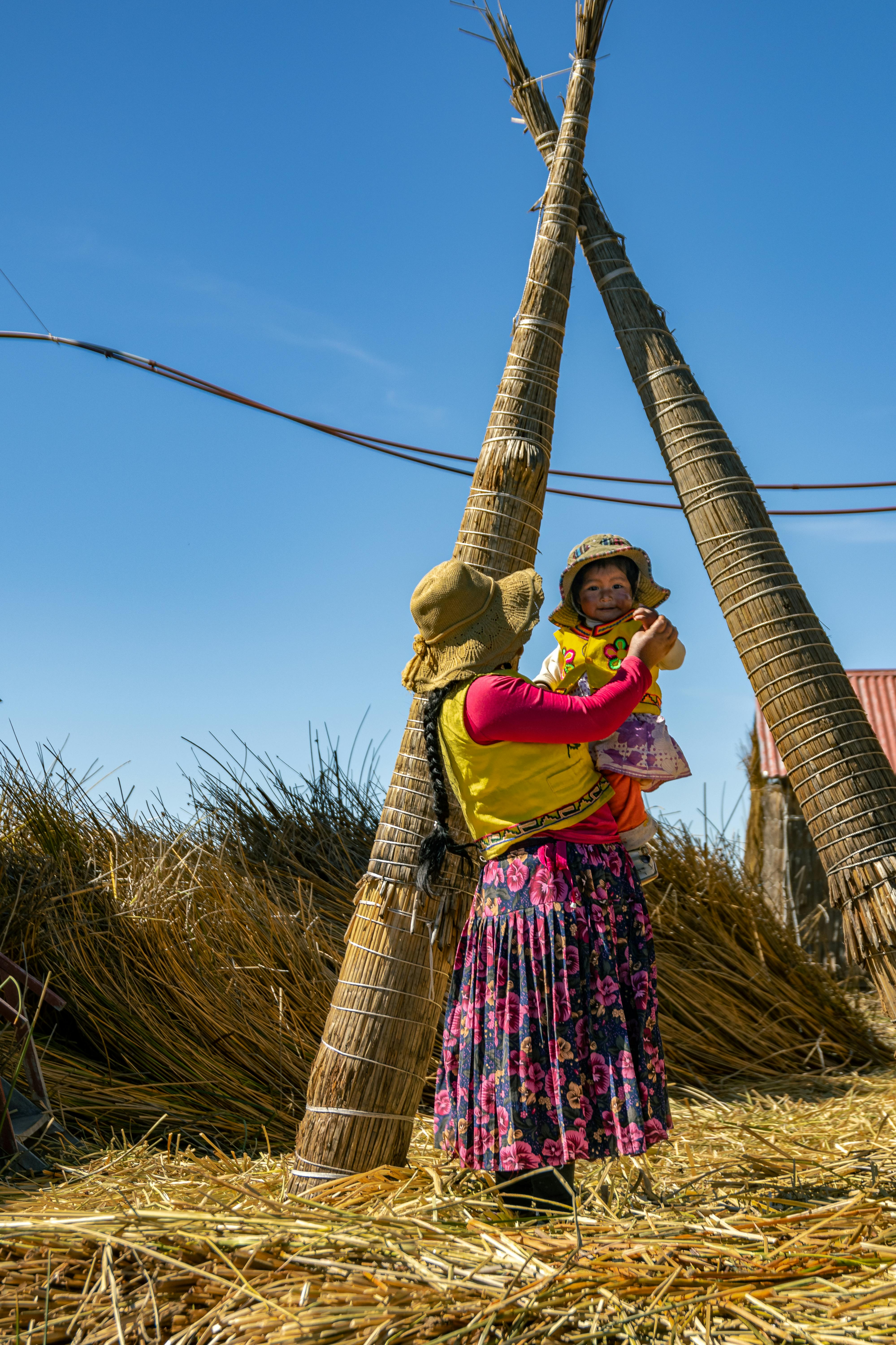 a woman and child standing in front of straw