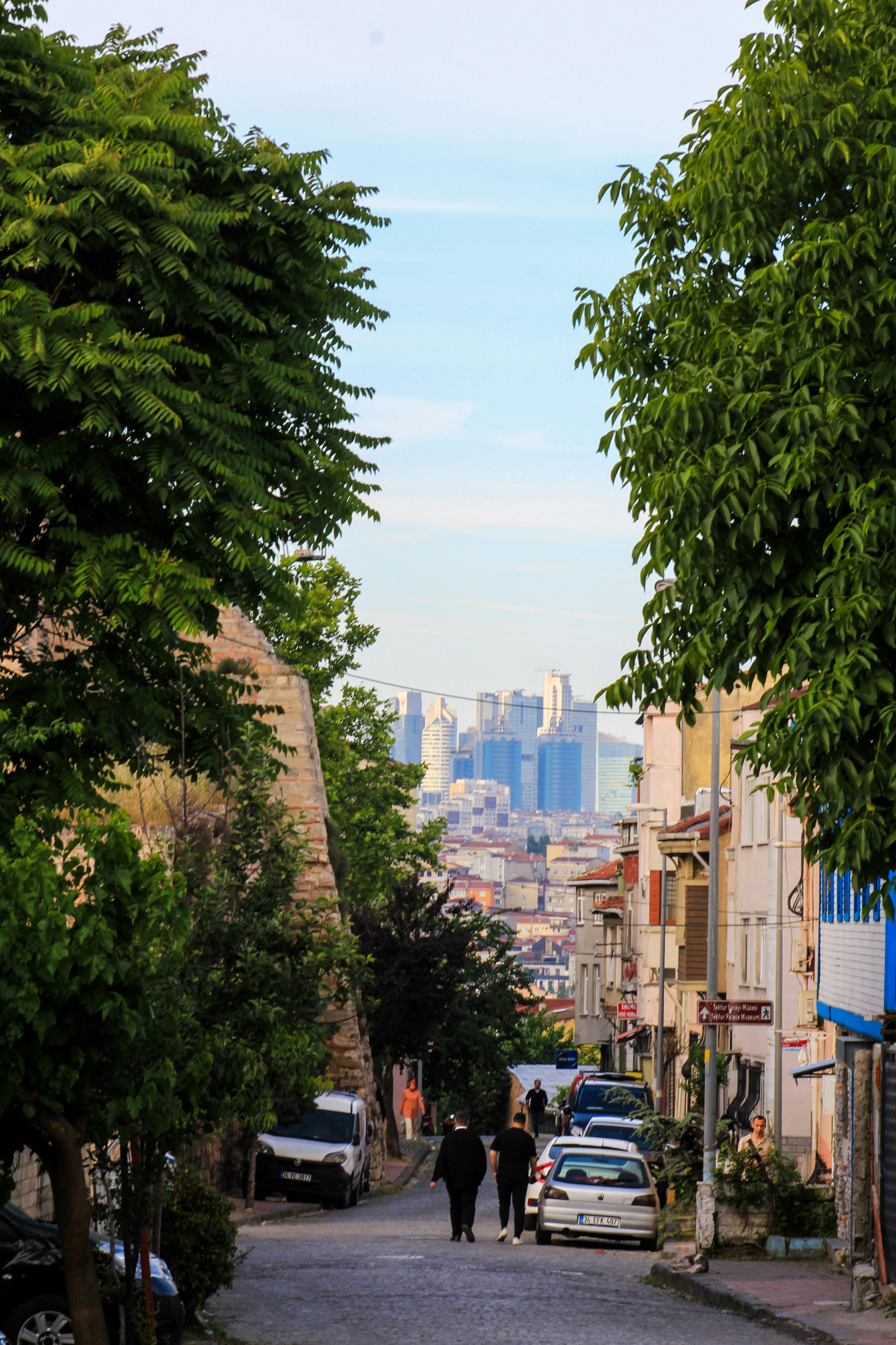 A person walking down a narrow street with a city in the background