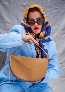 Fashion-forward woman in blue suit showcasing trendy handbag and sunglasses for a stylish look.