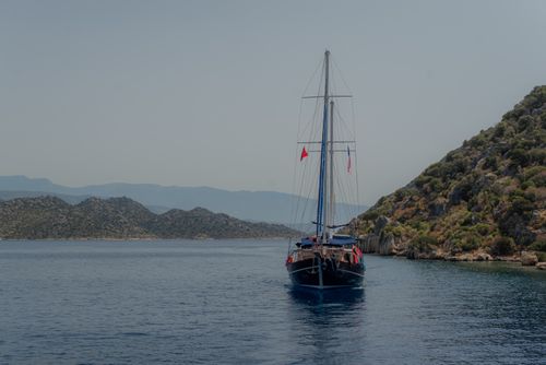 Free A picturesque yacht sailing through the tranquil waters of Antalya, Turkey, with lush green hills in the backdrop. Stock Photo