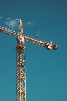 A large construction crane stands tall against a bright blue sky.