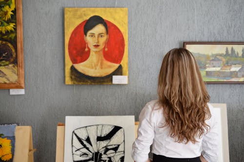 Free Woman Looking At Paintings Displayed On The Wall Stock Photo