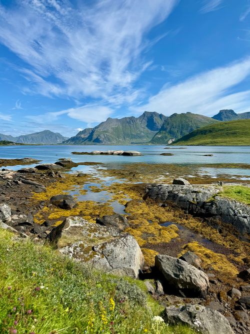Free Breathtaking view of a rocky coastline with clear skies and distant mountains, perfect for travel inspiration. Stock Photo