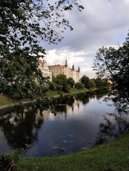 平静的湖泊倒映着一座历史建筑，四周环绕着郁郁葱葱的草木
