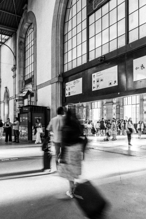 Free Travelers with luggage in motion at a bustling Porto railway station. Stock Photo