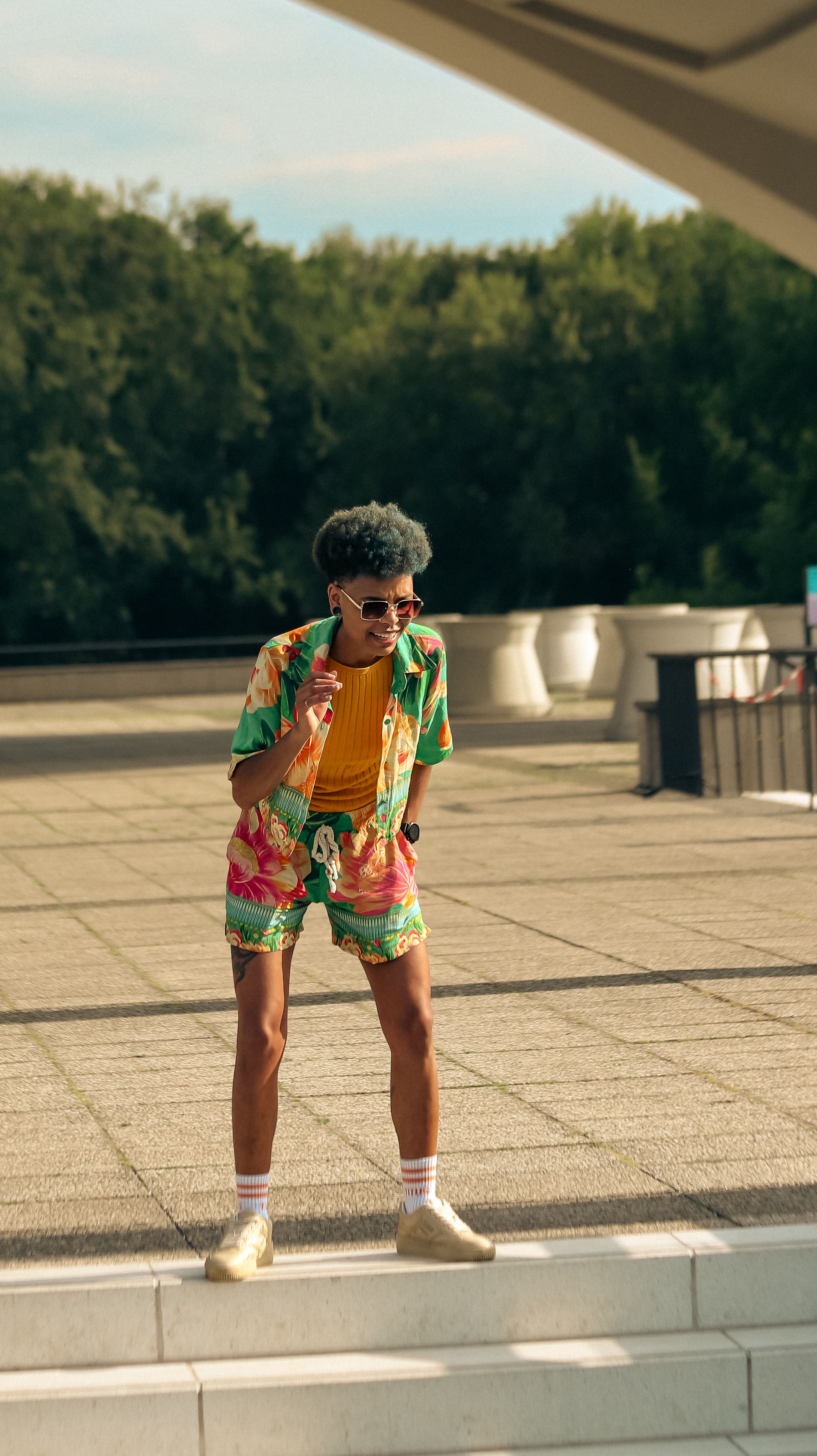 A fashionable young adult on a skateboard in a bright, summer outfit.