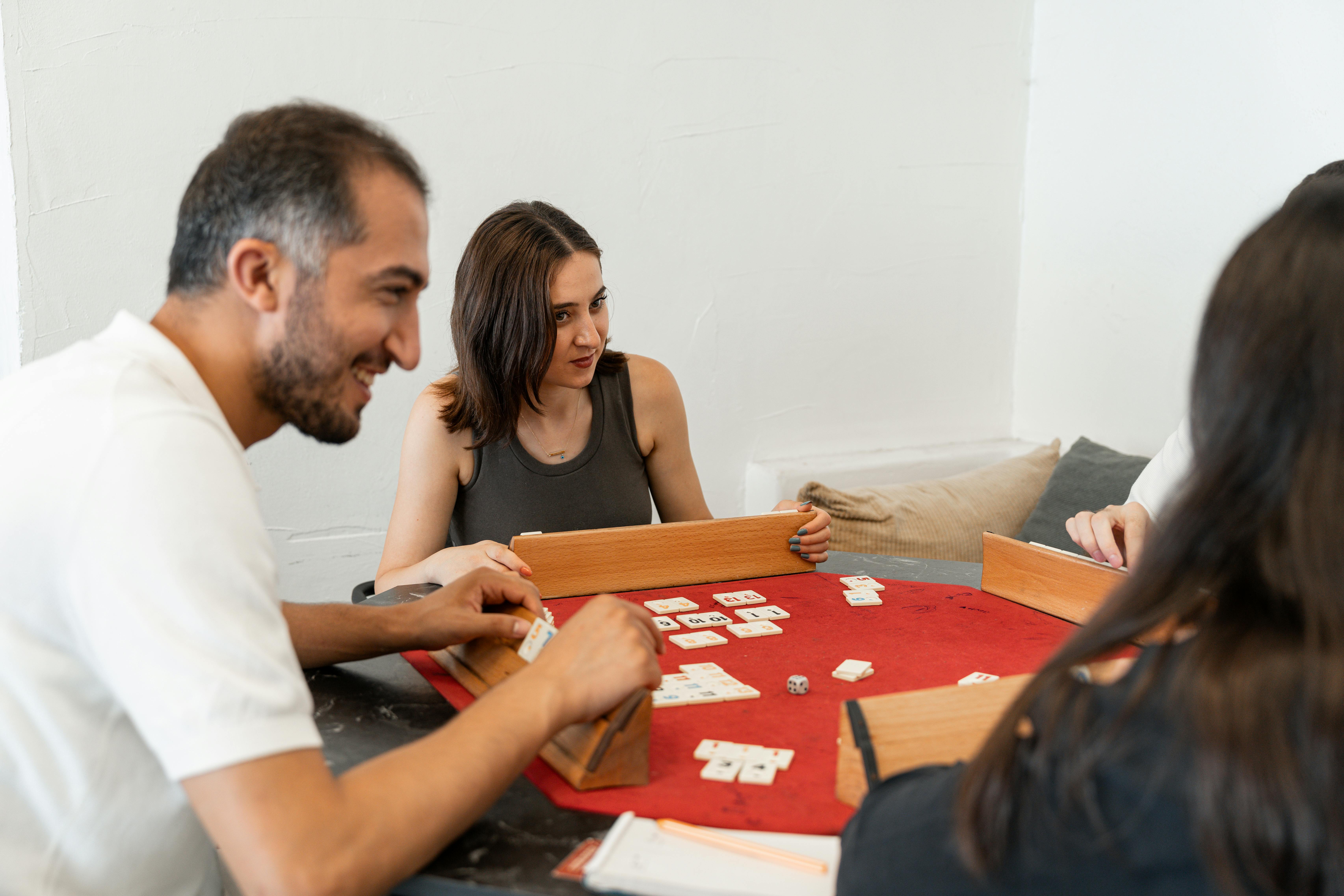 Adults enjoying a relaxing game of Rummikub together at home, focused and joyful.