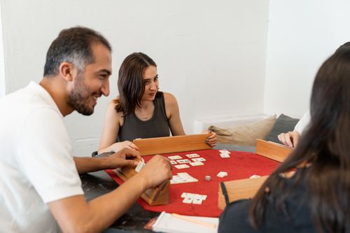Free Adults enjoying a relaxing game of Rummikub together at home, focused and joyful. Stock Photo