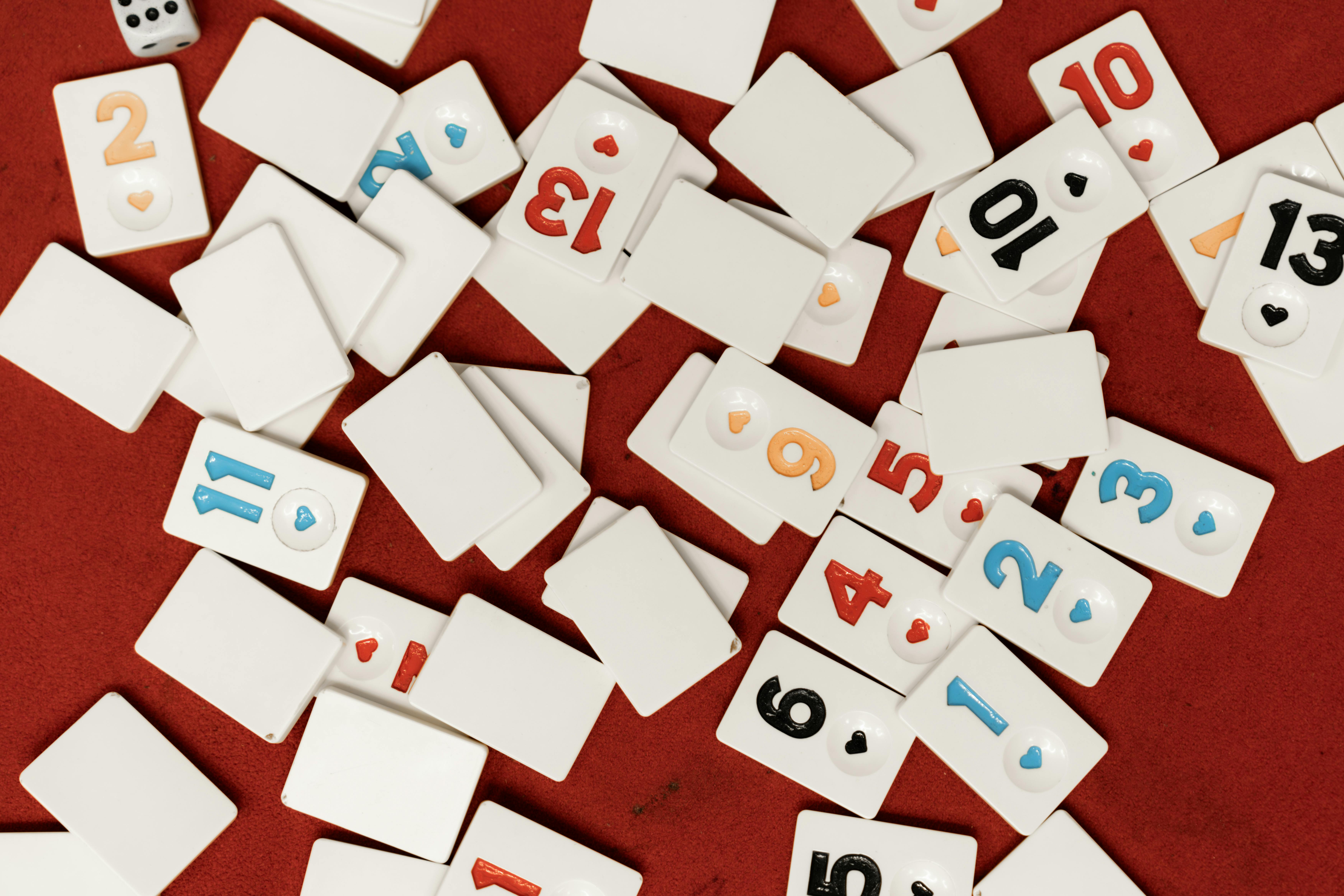 Scattered game tiles with numbers on a vibrant red surface, evoking themes of play and chance.