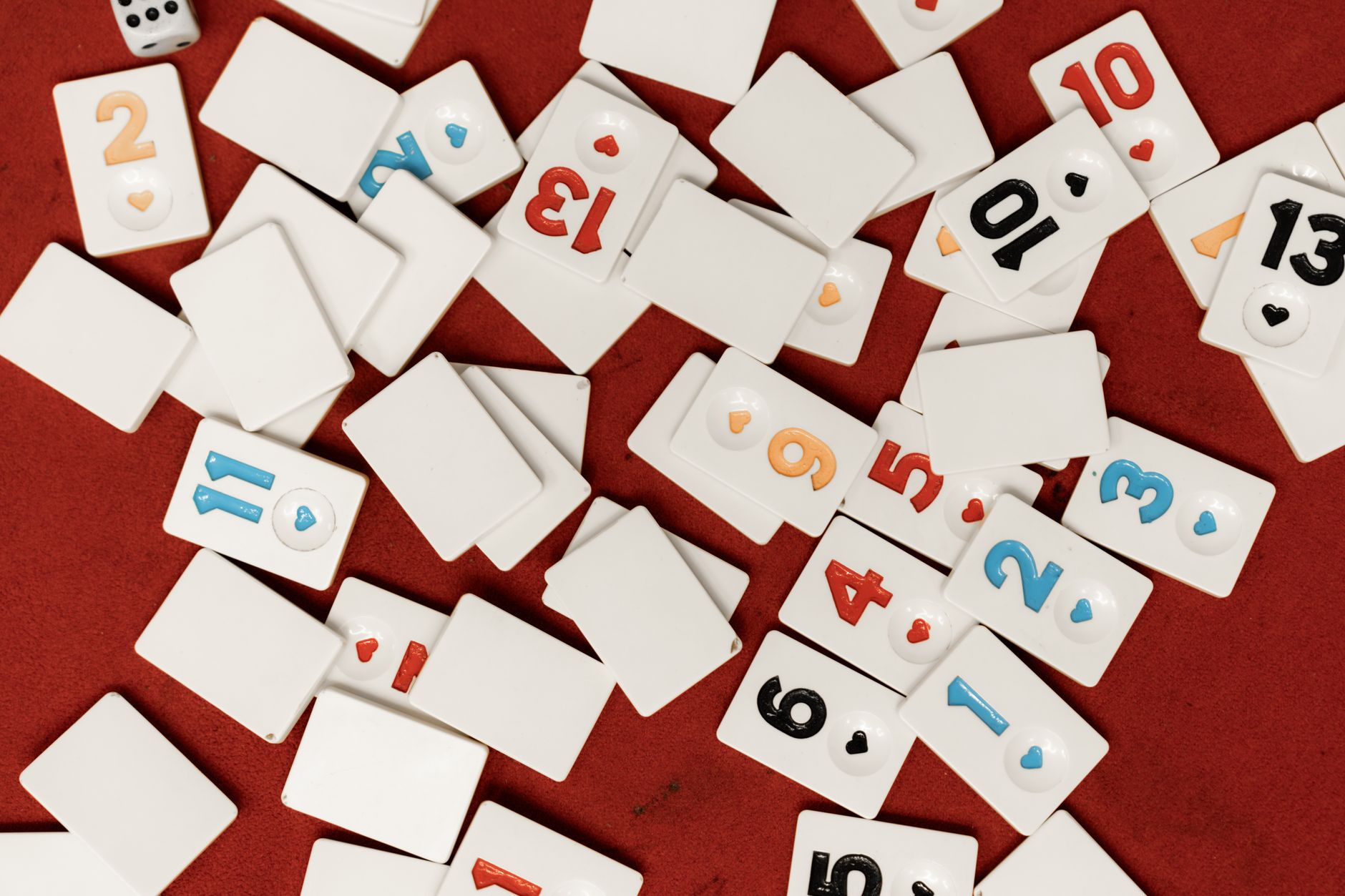 Scattered game tiles with numbers on a vibrant red surface, evoking themes of play and chance.