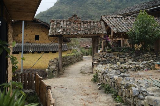 Explore rustic Vietnamese village architecture in Ha Giang featuring traditional wooden huts and stone pathways.