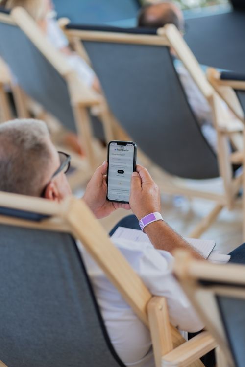 Free Elderly man sitting in a deckchair, browsing on smartphone outdoors. Stock Photo