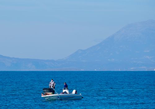 Free Two fishermen in a boat on the Adriatic Sea near the Albanian coastline with mountains in the background. Stock Photo