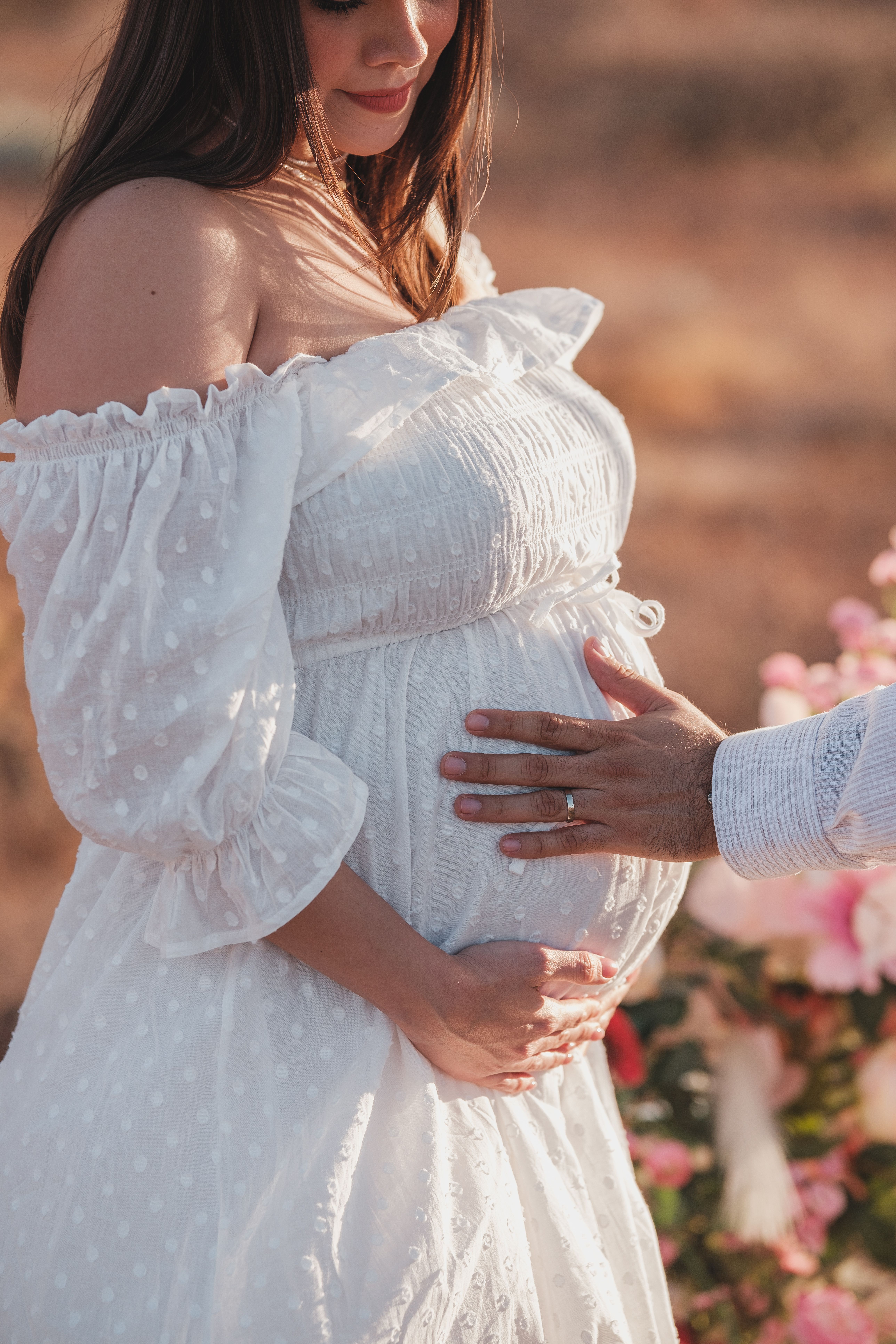 Fotomural Una pareja se abraza en un entorno de jardín pacífico, destacando un sereno momento de maternidad.