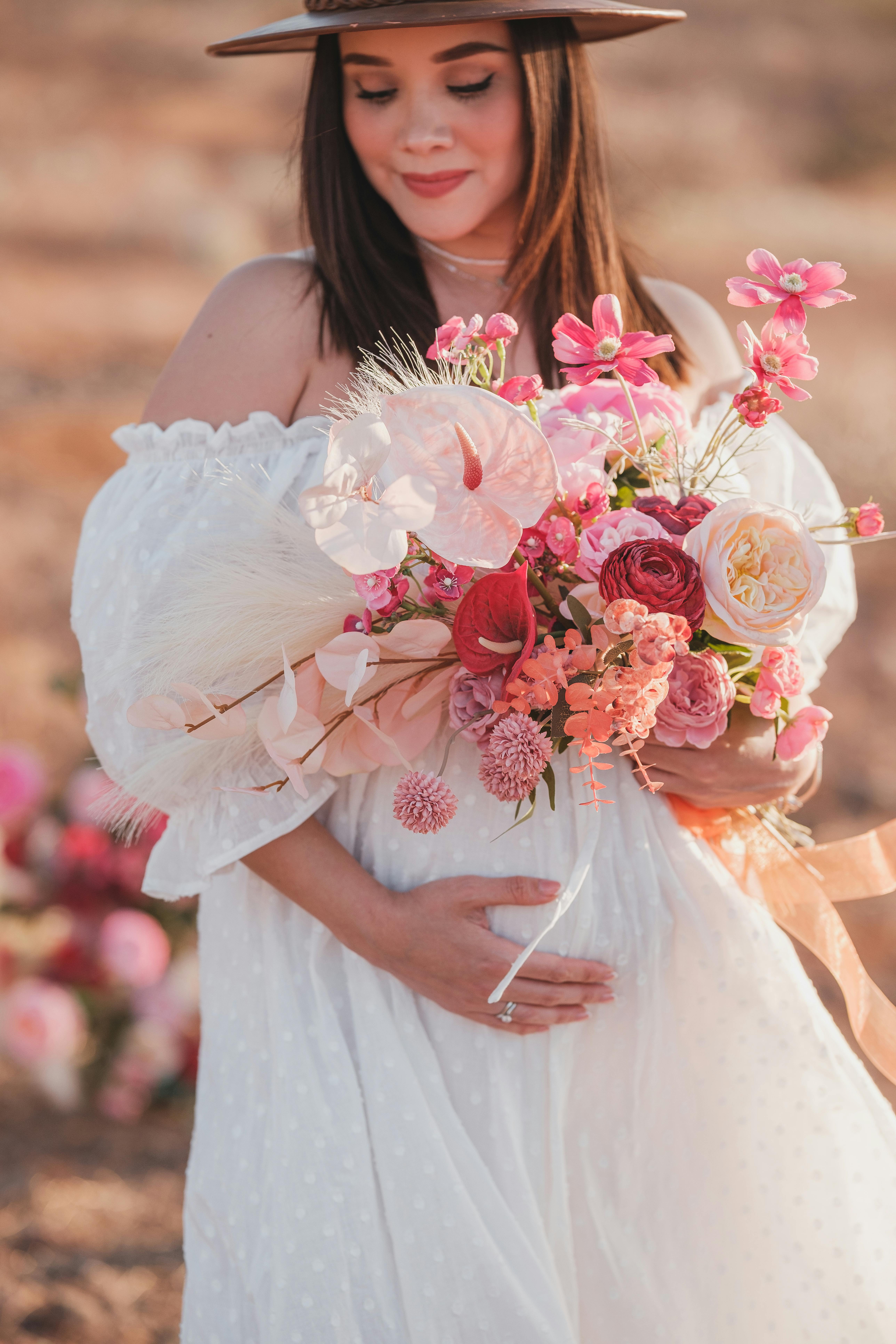 pregnant woman in white dress and with flowers bouquet