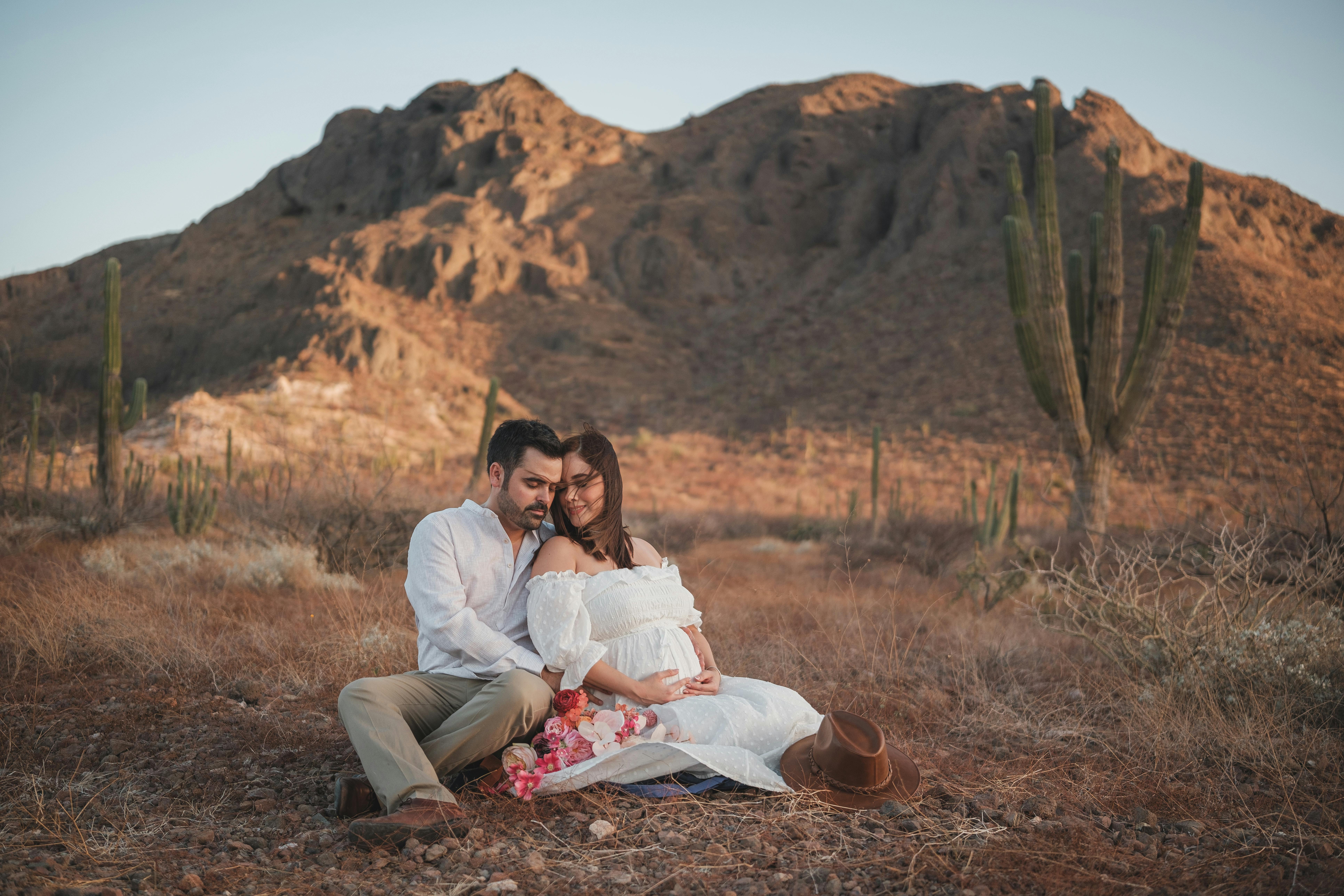 man sitting and hugging pregnant woman in countryside