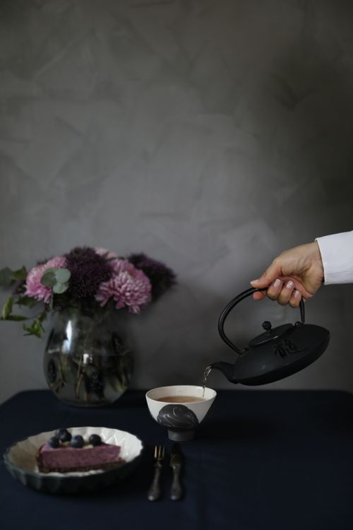 Free A serene tea pouring scene with a floral arrangement, exuding calmness. Stock Photo