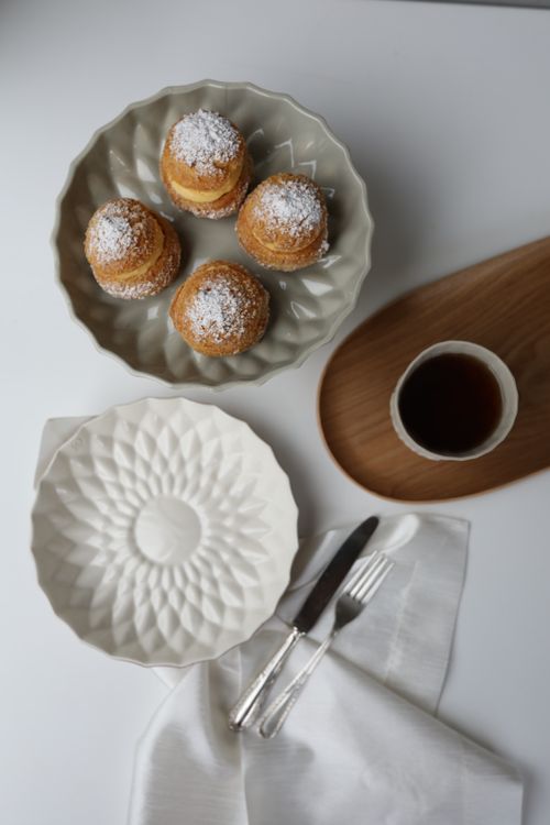 Free A top view of pastries with powdered sugar beside a cup of coffee on a table. Stock Photo