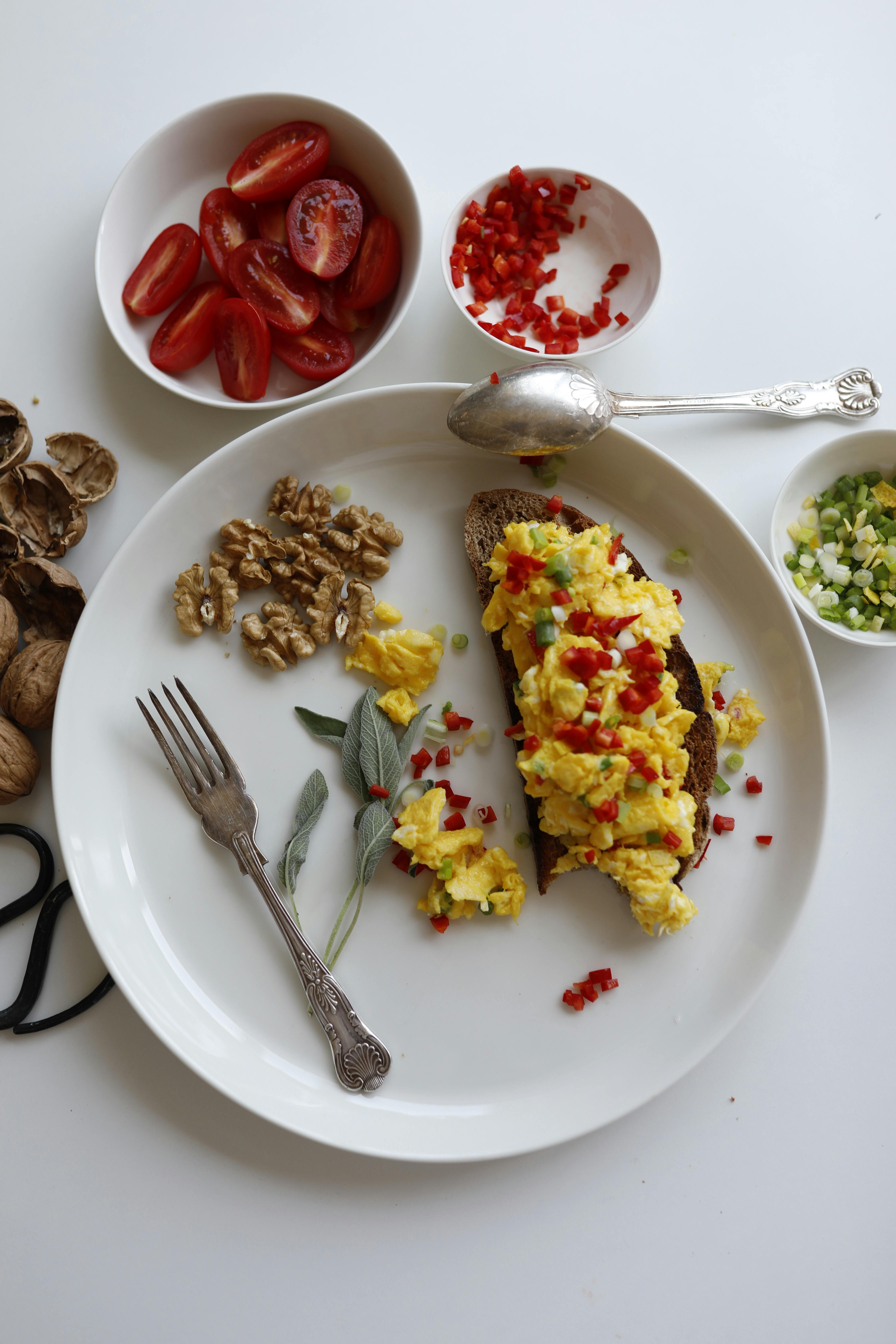 A nutritious breakfast plate with scrambled eggs on toast, tomatoes, and walnuts.