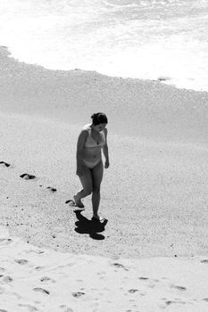 Black and white photo of a woman walking on the beach at Matosinhos, Portugal.