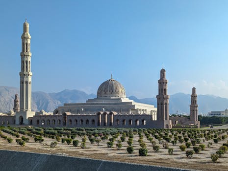 Sultan Qaboos Grand Mosque with its striking minarets against a clear blue sky in Muscat, Oman.