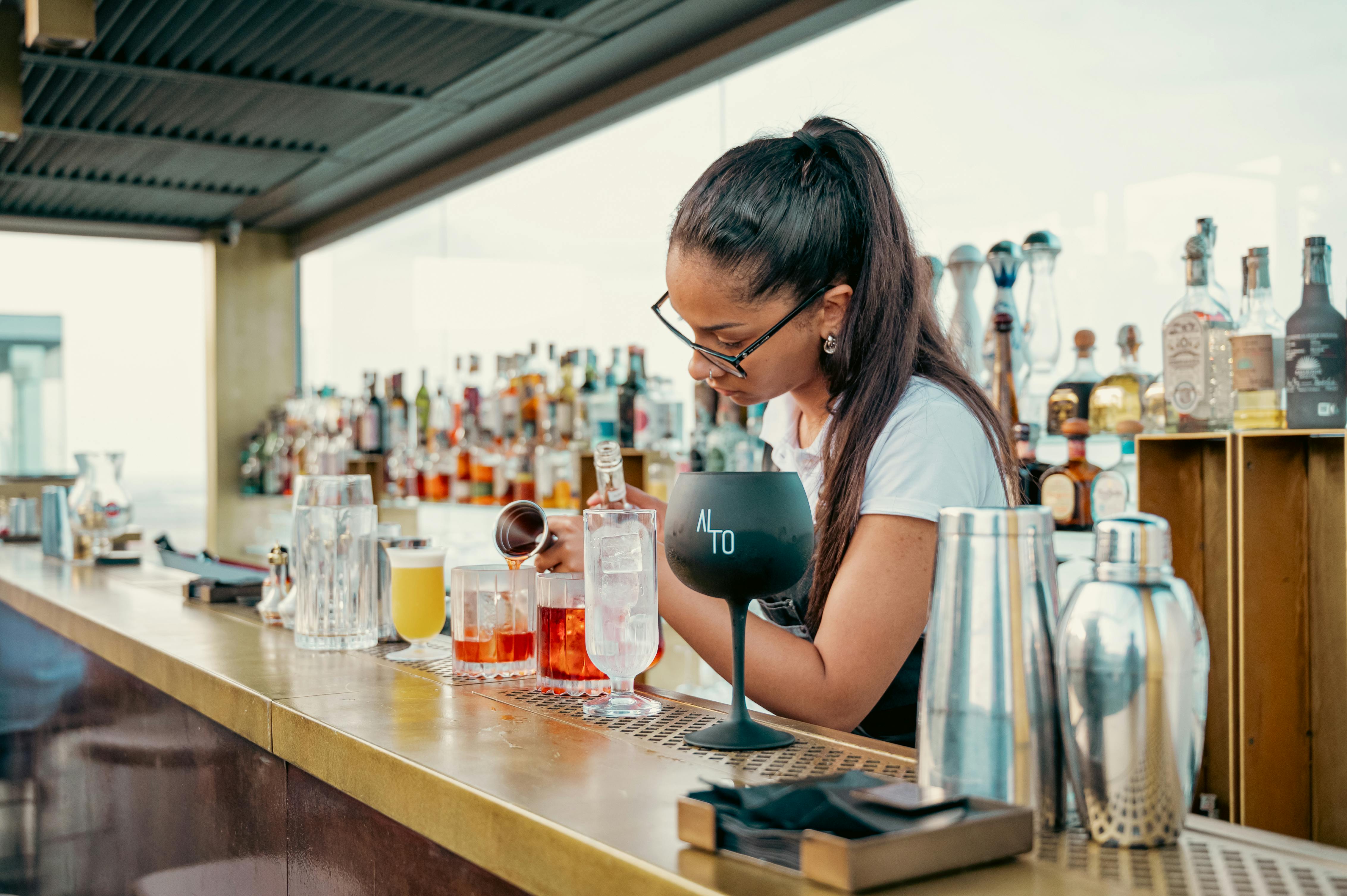 a woman is making drinks at a bar