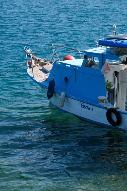 Free A peaceful scene of a traditional blue fishing boat anchored on calm waters, capturing maritime life. Stock Photo