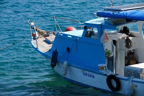 Free A vibrant blue boat docked in calm coastal waters, perfect for a serene marine-themed escape. Stock Photo
