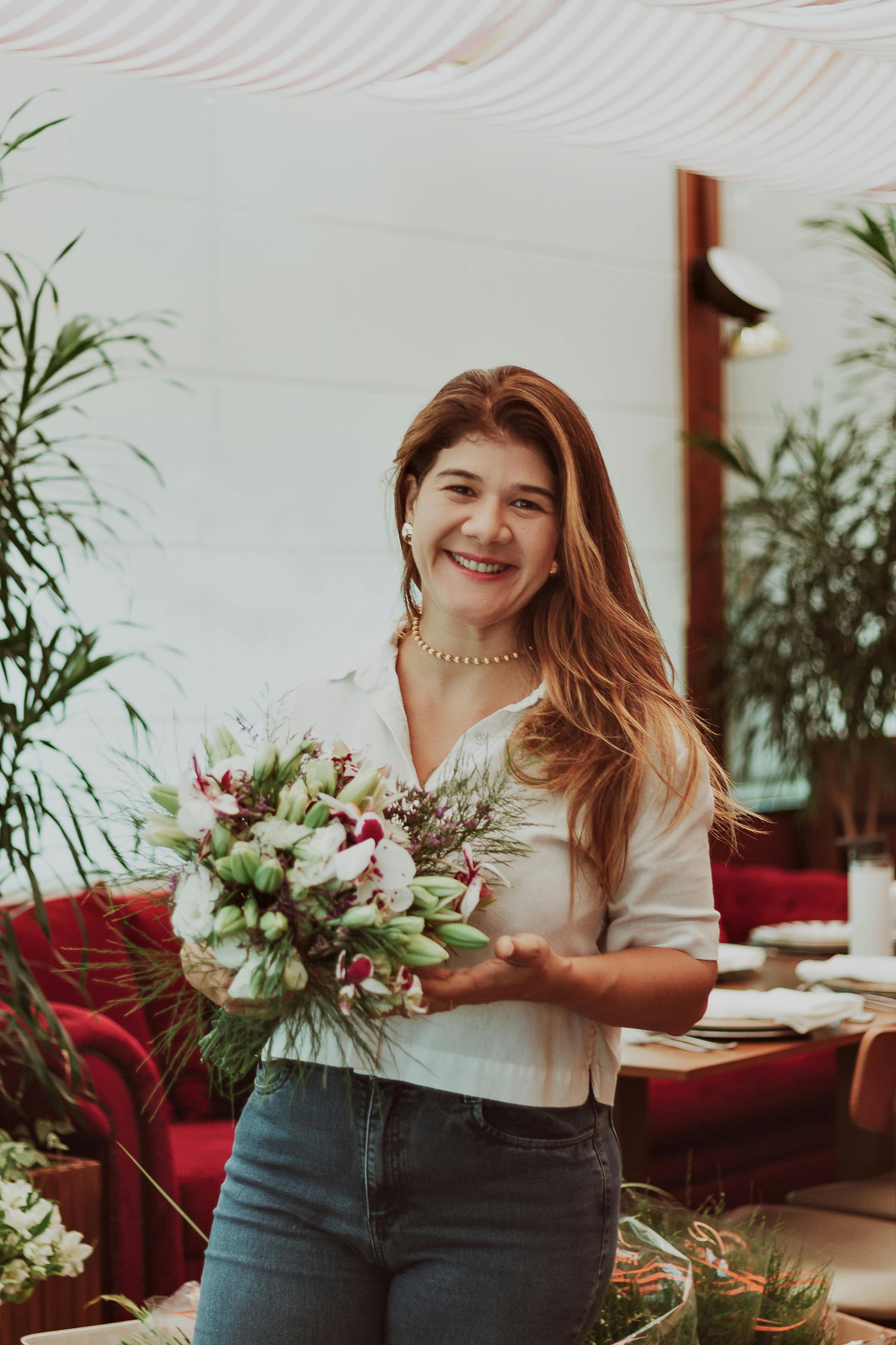 Portrait of a smiling woman holding a bouquet inside a decorated room with red furniture.